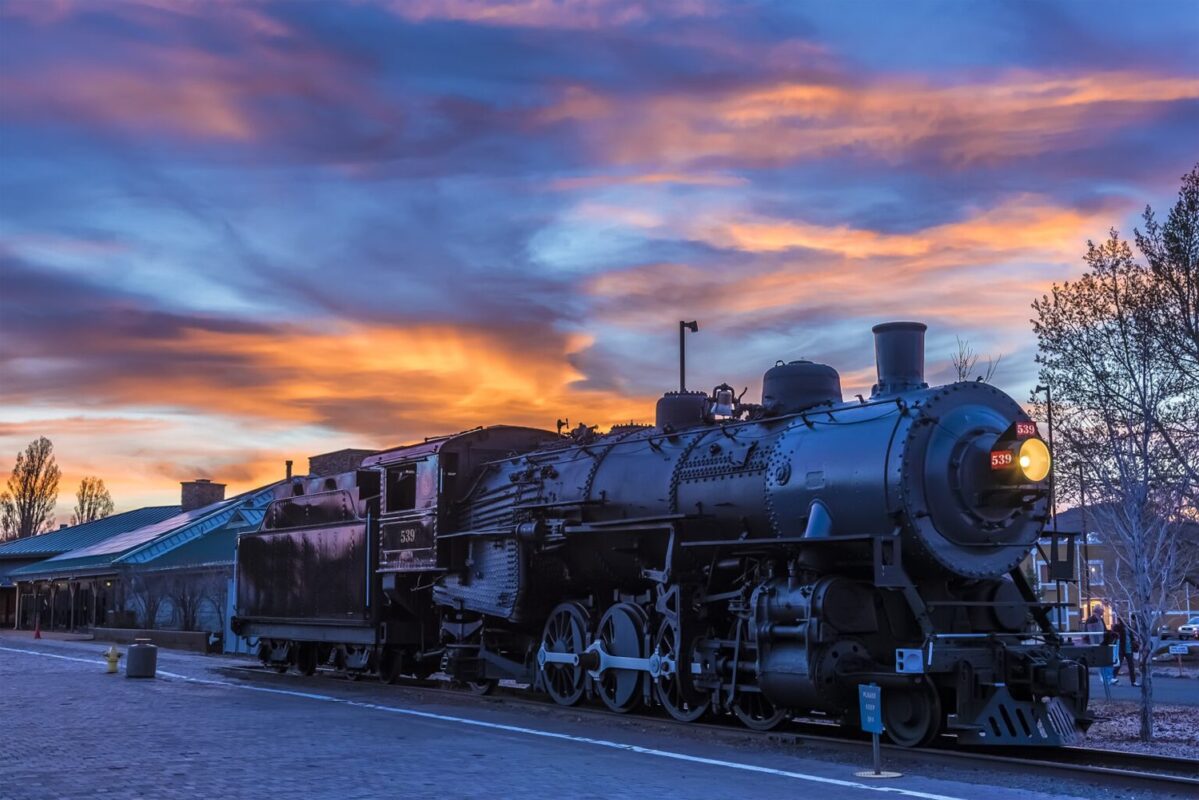 The train to the Grand Canyon waiting at Williams Station, Arizona illuminated by a fiery sunset sky.