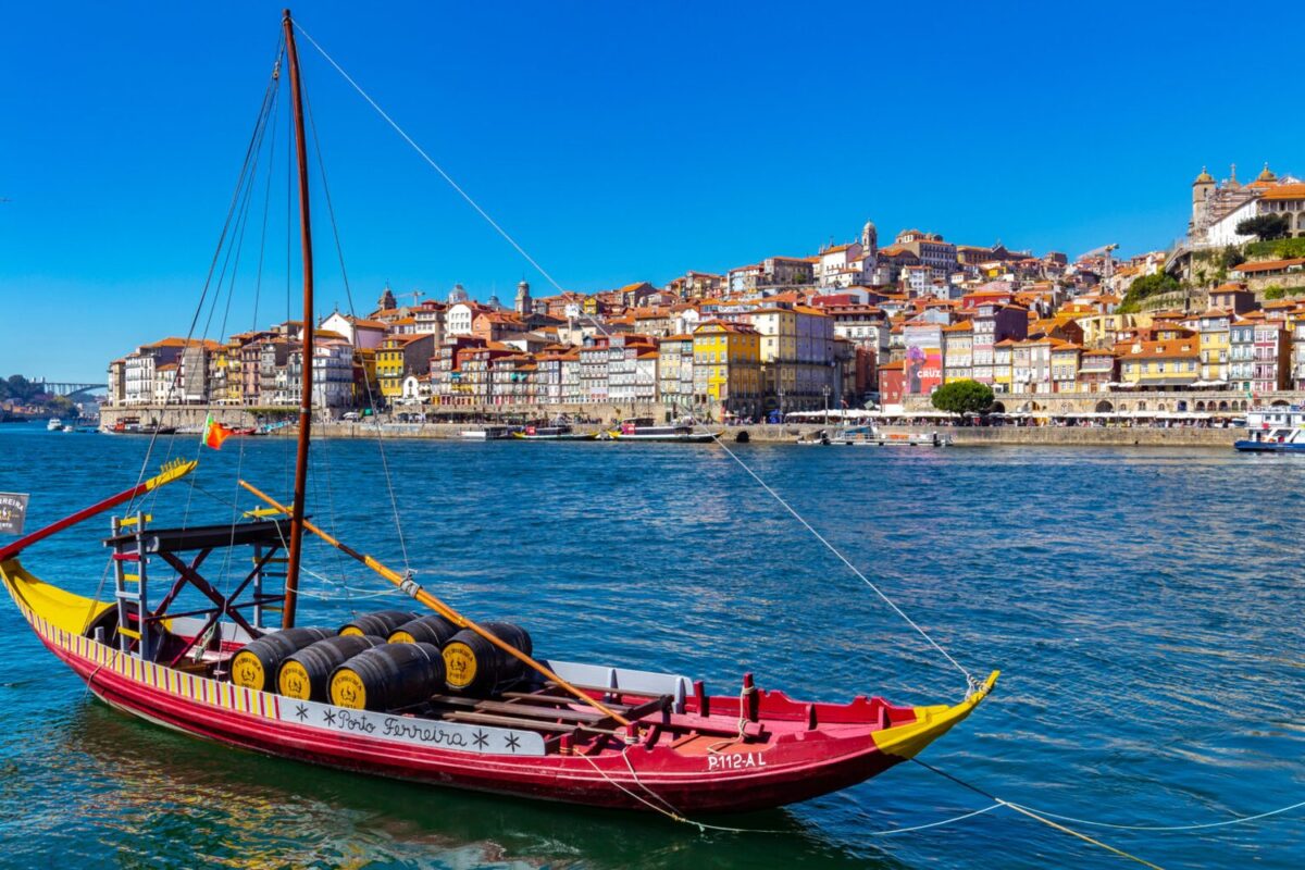 PORTO, PORTUGAL – CIRCA SEPTEMBER, 2017: Boat anchored on the Douro River with the Cais da Ribeira in the background, in the city of Porto, Portugal