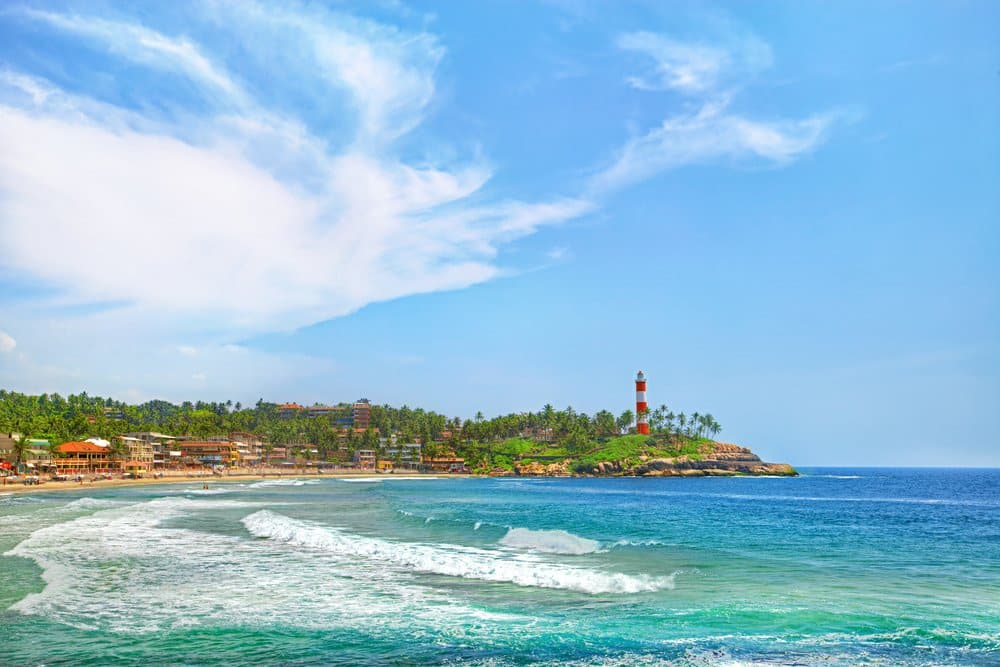 Kerala province beach in India with a vivid lighthouse in the ocean.