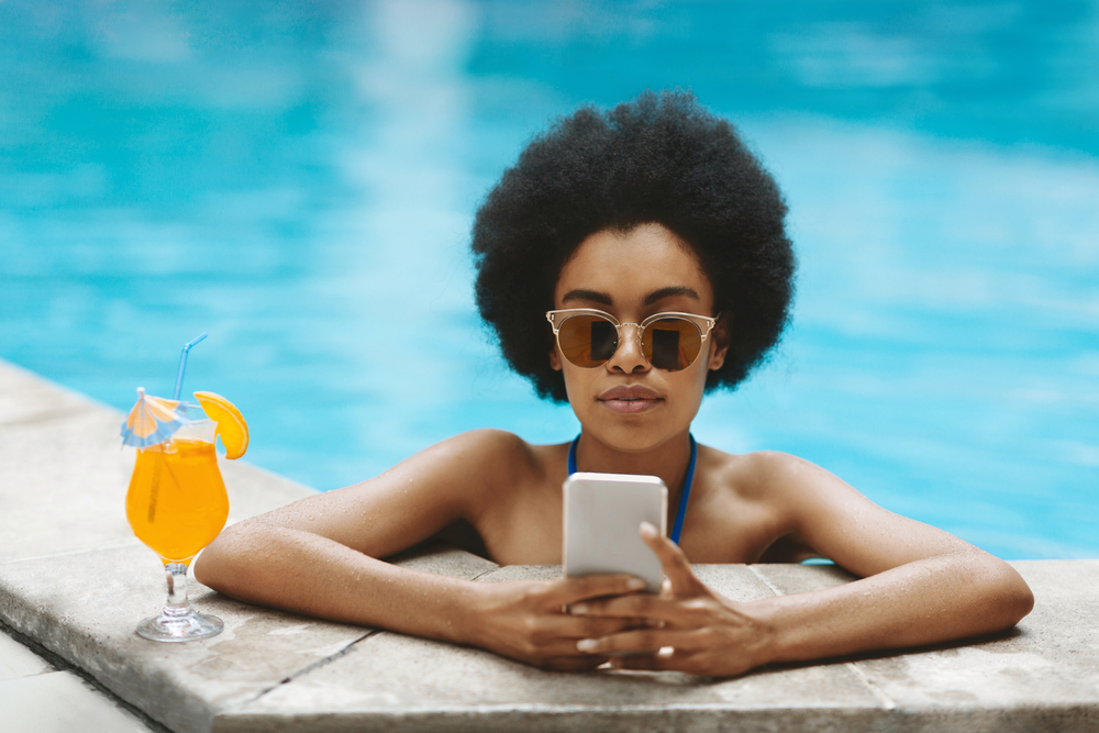 Gorgeous Black Lady With Tropical Cocktail Using Smartphone At Outdoor