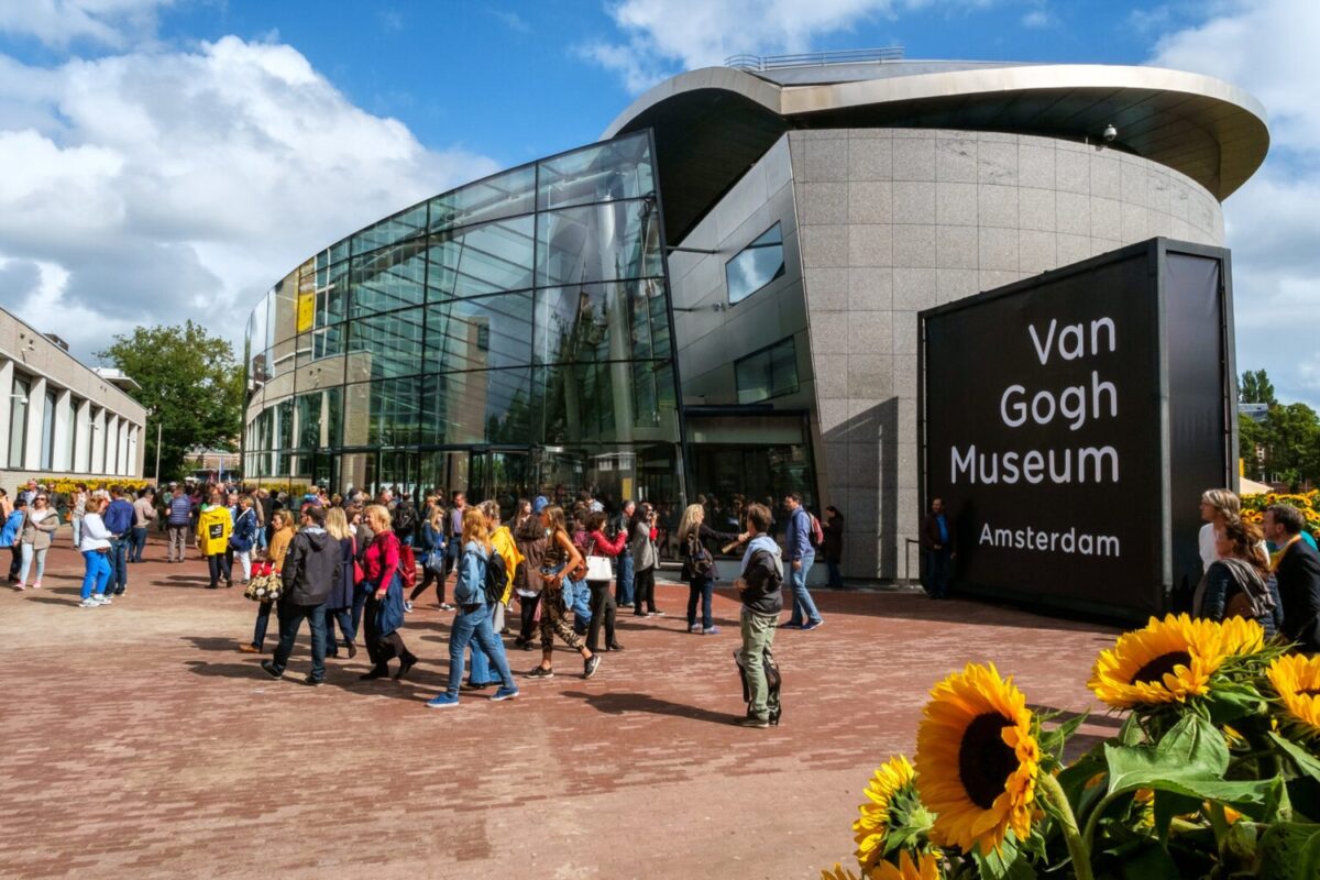 Crowd in front of the new wing of the Van Gogh Museum with sunflowers in the foreground.