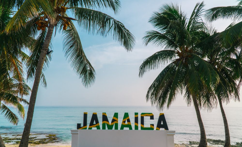 The Jamaican flag is displayed in front of one of the best beaches in Jamaica – Negril Beach, Jamaica.