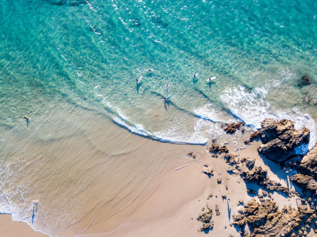 The Pass at Byron Bay from an aerial view with blue water.