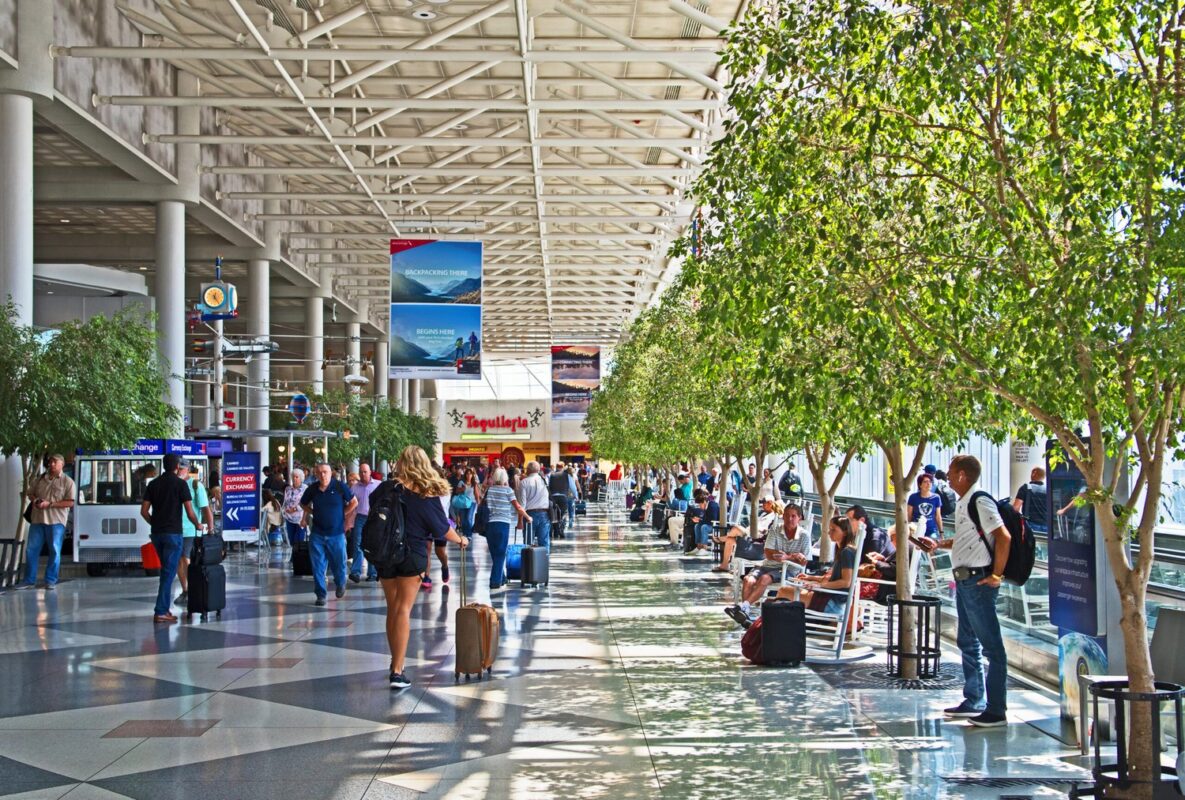 Light streams through the glass facade of the tree lined and busy central concourse at Charlotte Douglas International airport.