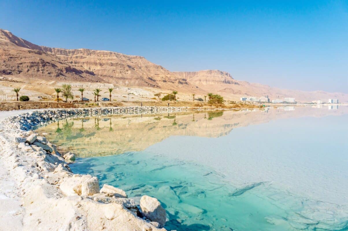 Dead Sea coastline with white salt beach and mountains at sunny day in Ein Bokek, Israel. White mineral salt shore at Dead sea, Israel.