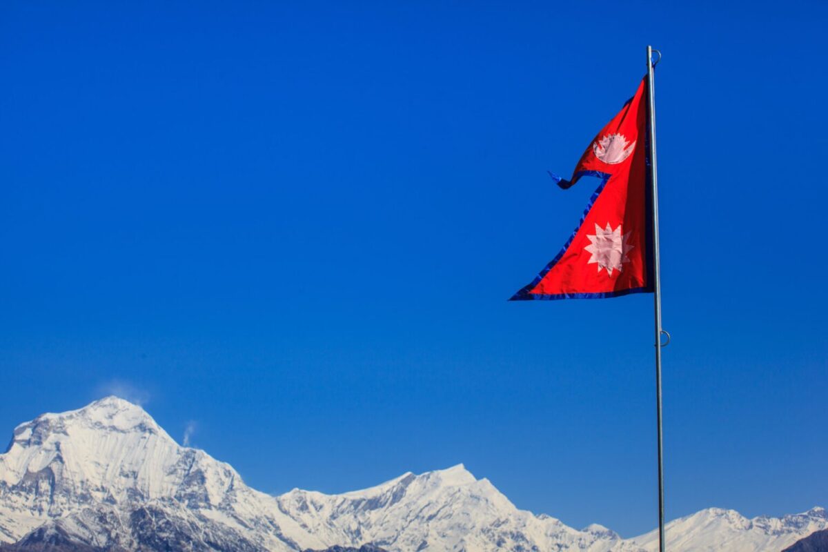 The triangular flag of Nepal flying with the Himalayas in the background at Poon Hill.