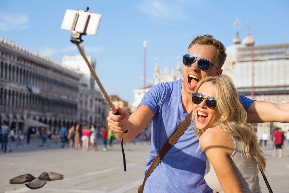 Funny tourist couple making selfie with selfie stick