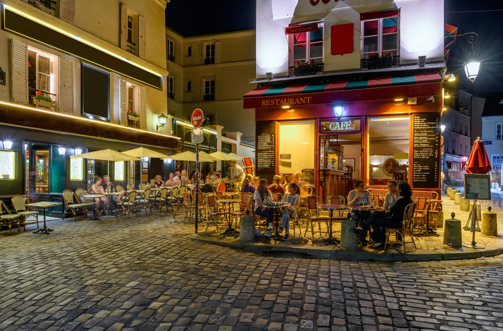 Typical night view of cozy street with tables of cafe in quarter Montmartre in Paris, France.