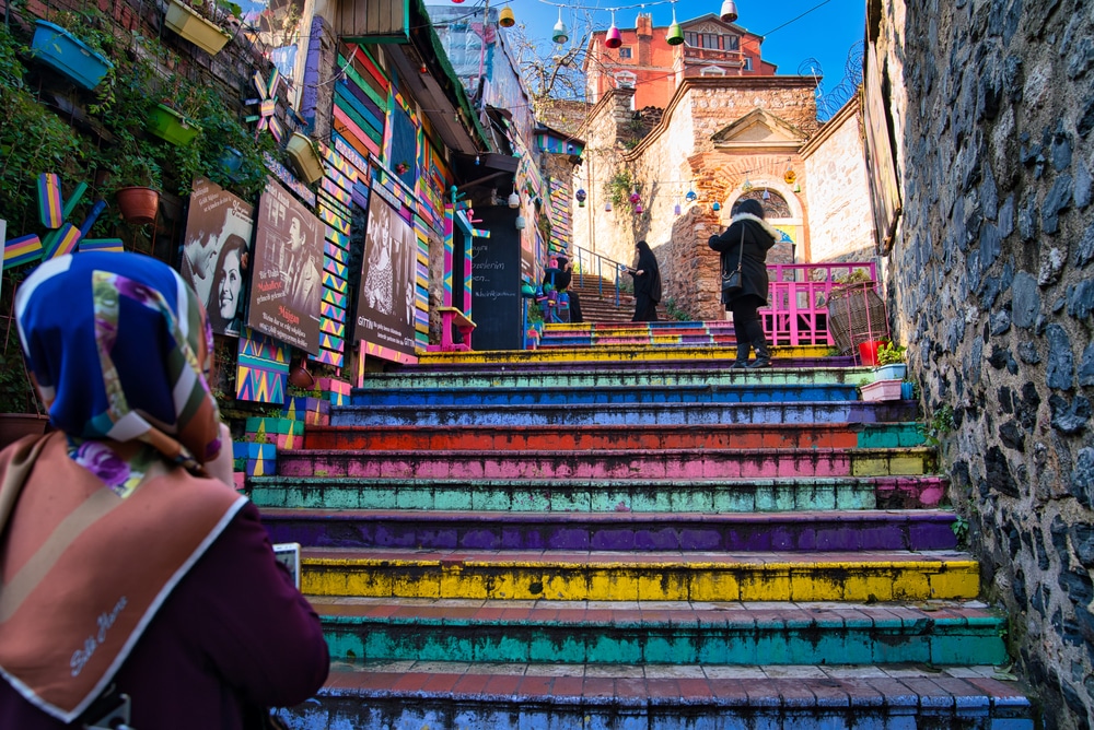 Istanbul, Turkey - January 10, 2020 Beautifully multi colored Rainbow stairs, in Balat district heading up to some buildings, surrounded by paintings on the side and some local people going up.