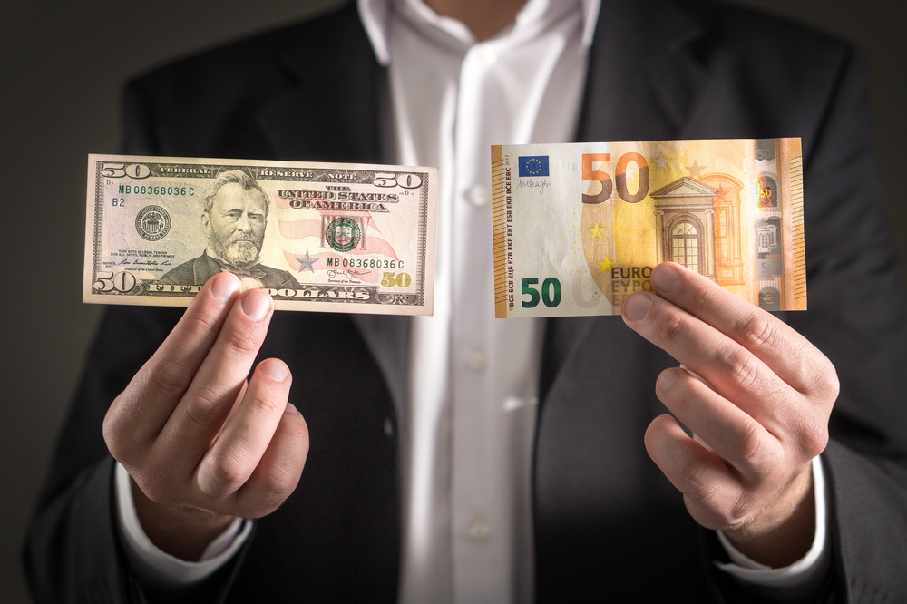 Dollar vs euro. Business man in suit holding 50 banknote and bill in both currency in hand.